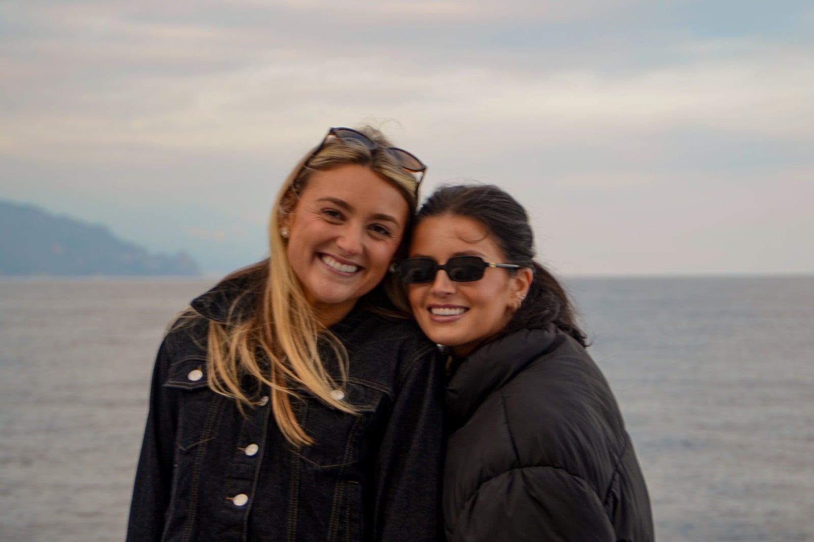 Two friends smiling on board, with the sea behind them