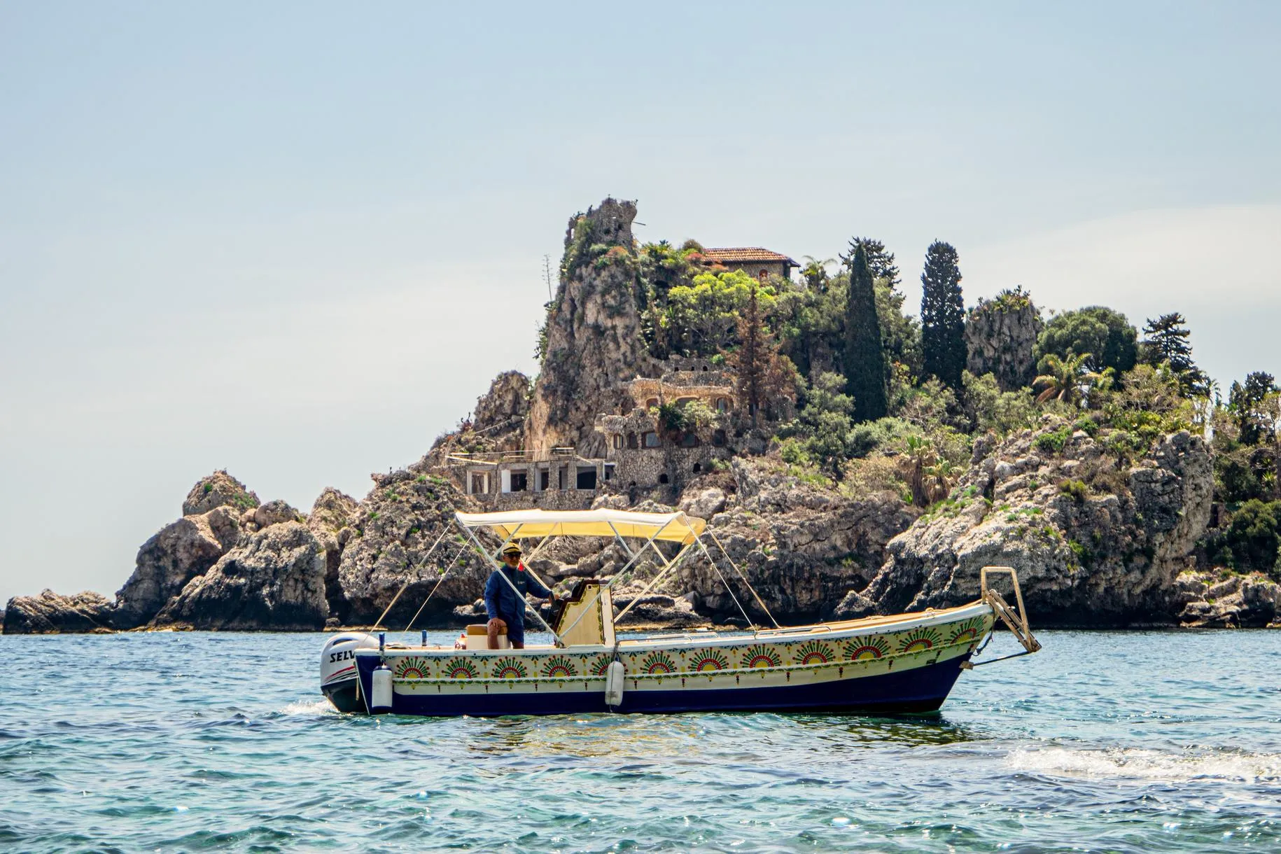 Our traditional Sicilian boat, with colourful hull decorations and a sun canopy, in front of Isola Bella